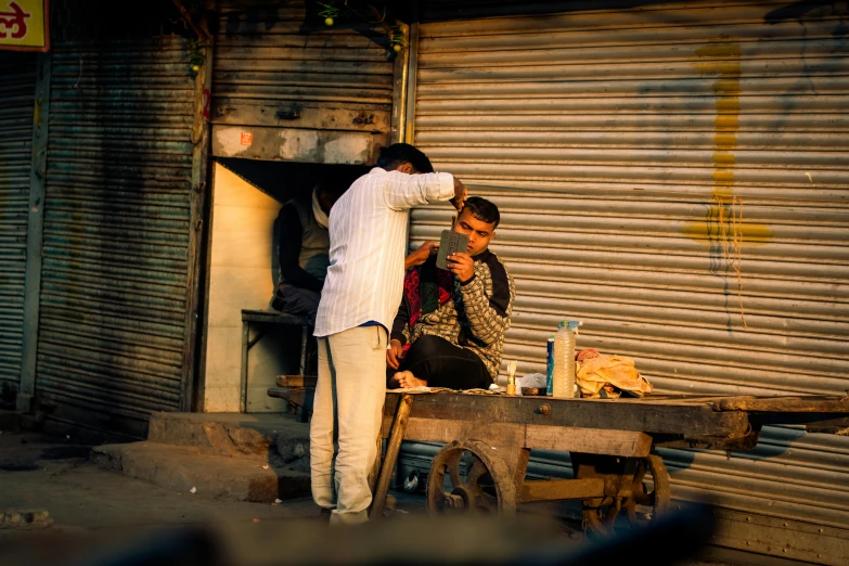 a young man standing next to an old woman outside of a garage