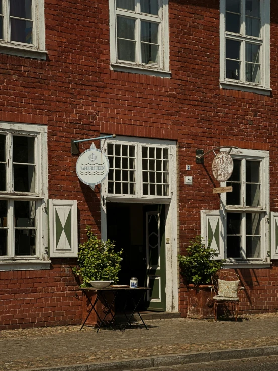 a red brick building that has two plants in front of the windows