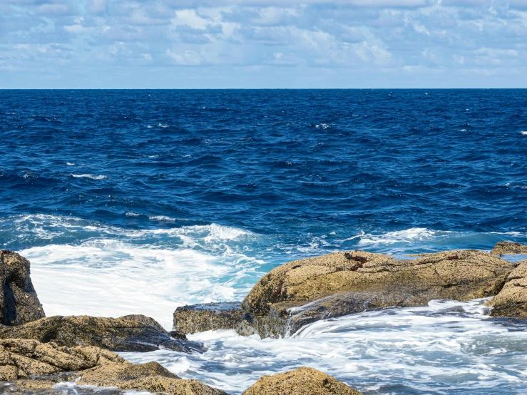 two people on a rock overlooking the ocean