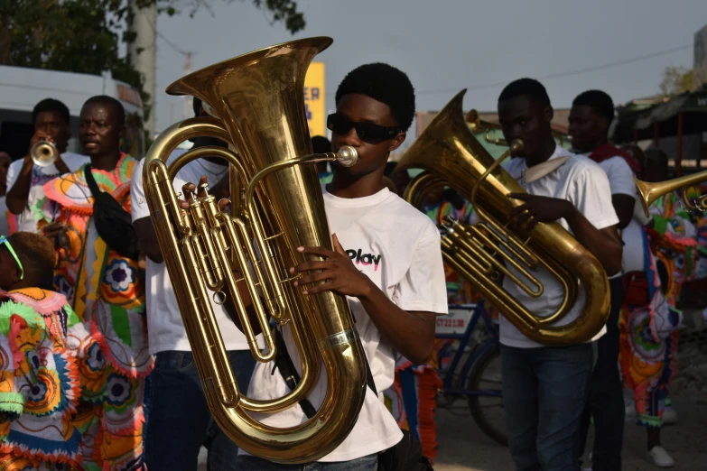 man holding an instrument and several others are wearing colorful clothing