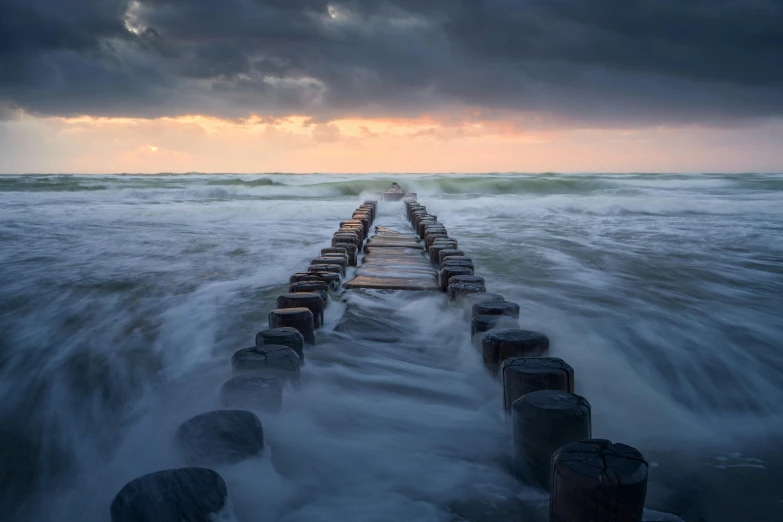 a long wooden pier surrounded by turbulent water