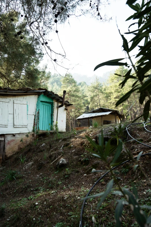 a run down house sits on the side of a hill