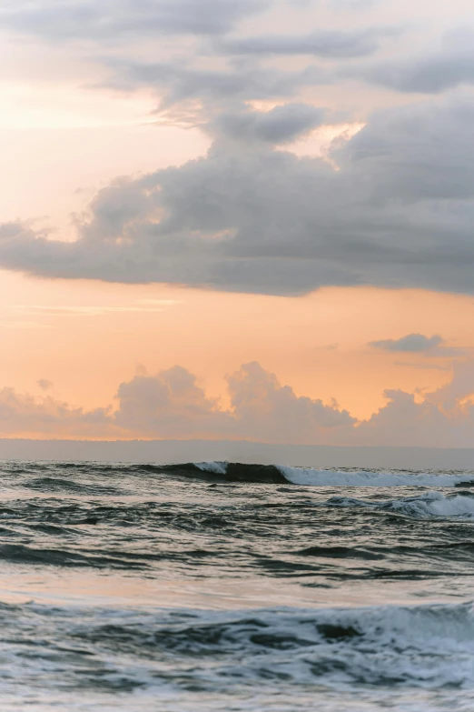 waves rolling in towards the shore and one man surfing in the ocean