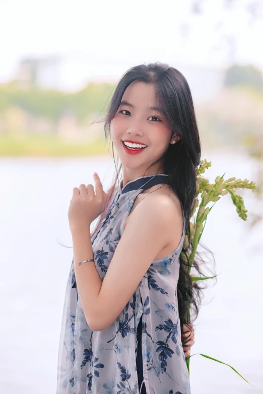 a young woman smiles at the camera, next to water