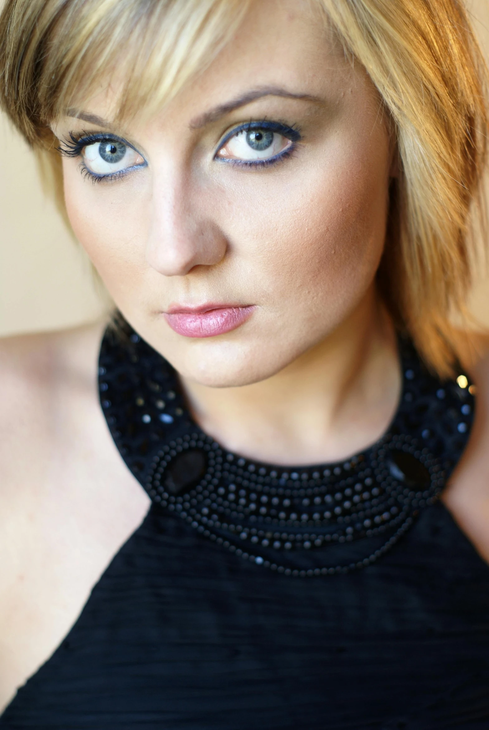 a beautiful blond woman with blue eyes and dark makeup