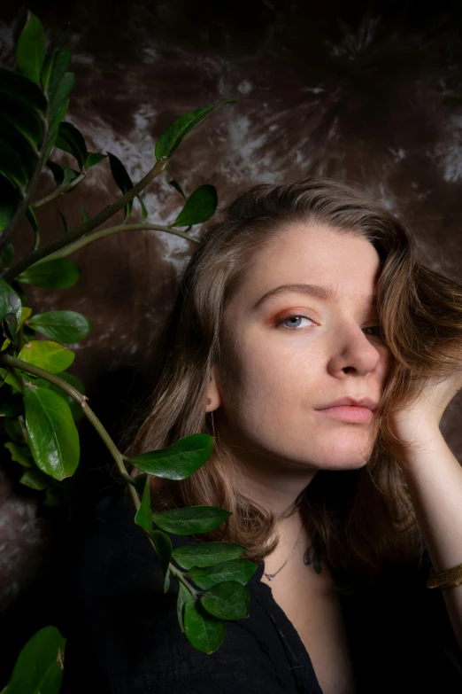 a woman in a black shirt is holding her head near plants