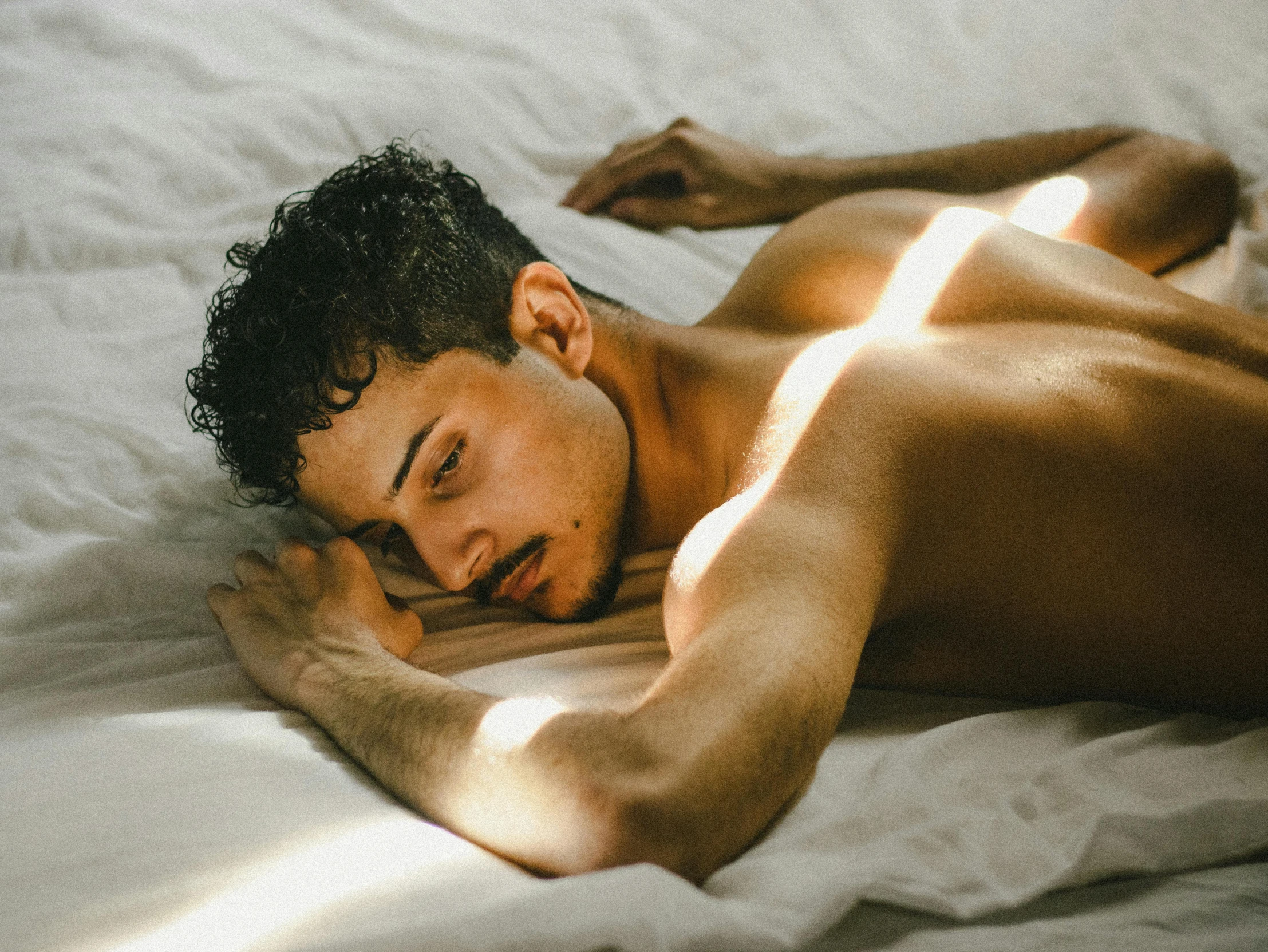 a man laying on top of a white bed