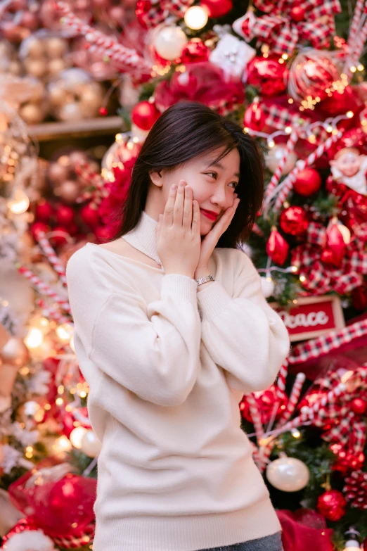 a woman smiles as she stands in front of a christmas tree