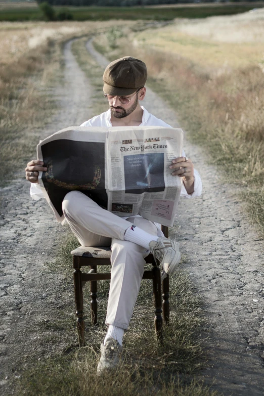 a man sitting on a chair reading a newspaper