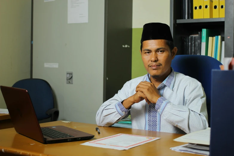 the man wearing a suit and sitting at his desk with a laptop