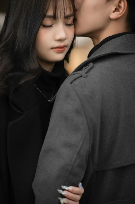 an asian man kissing the forehead of a young woman