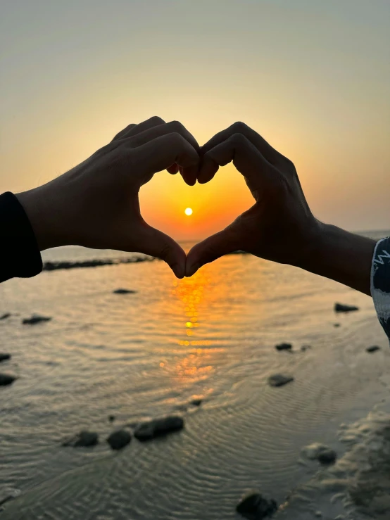 a couple of hands that are making a heart shape