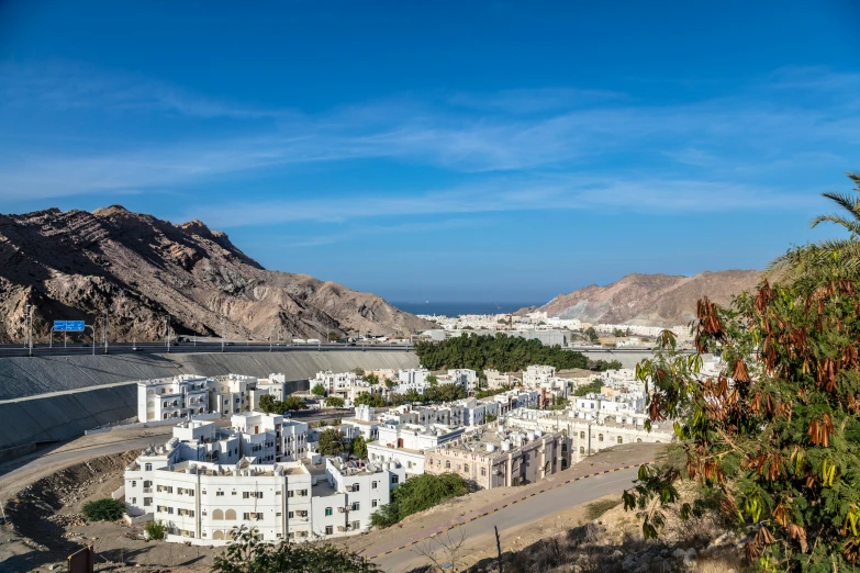 the white buildings sit on the road below mountains