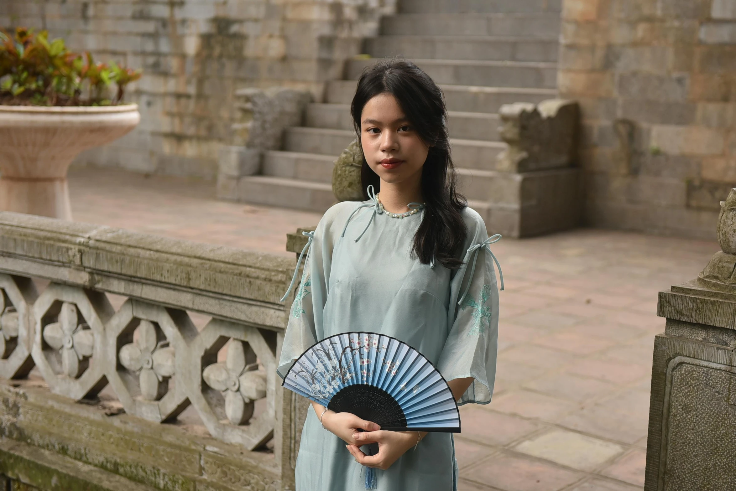 a woman in a dress is holding a chinese fan