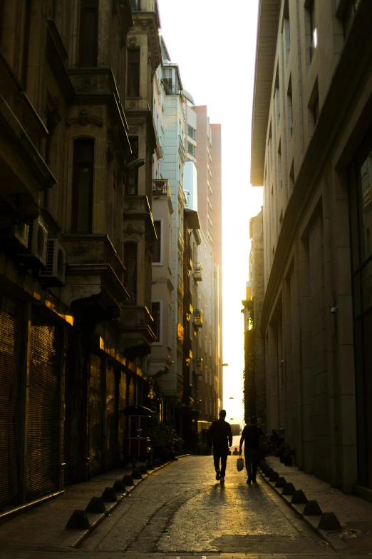 two people walking down a city street at dusk