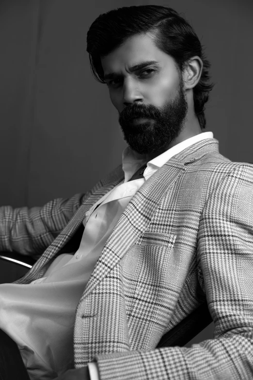 a man wearing a suit and tie sitting down