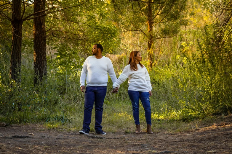 two people walking in the middle of some trees