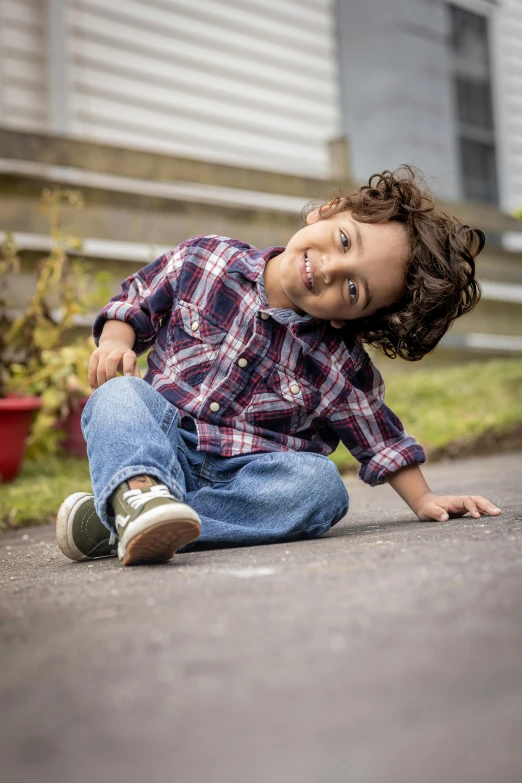 a little boy sitting on the ground outside