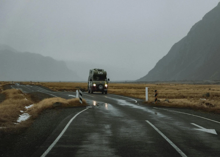 a truck that is driving down a rain soaked road