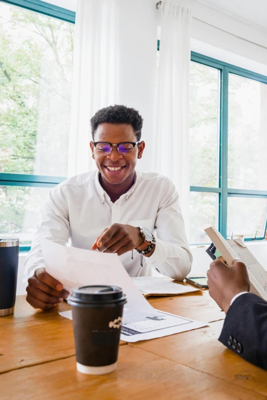 two men smiling as they look at some papers