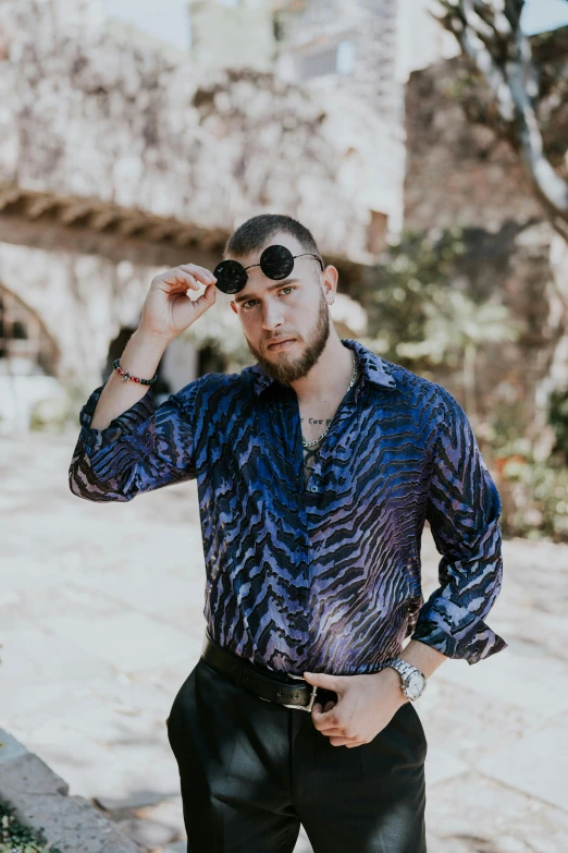 a man in sunglasses standing in front of a brick wall