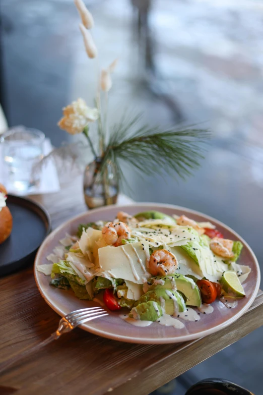 a plate with lettuce, tomatoes, cheese and shrimp