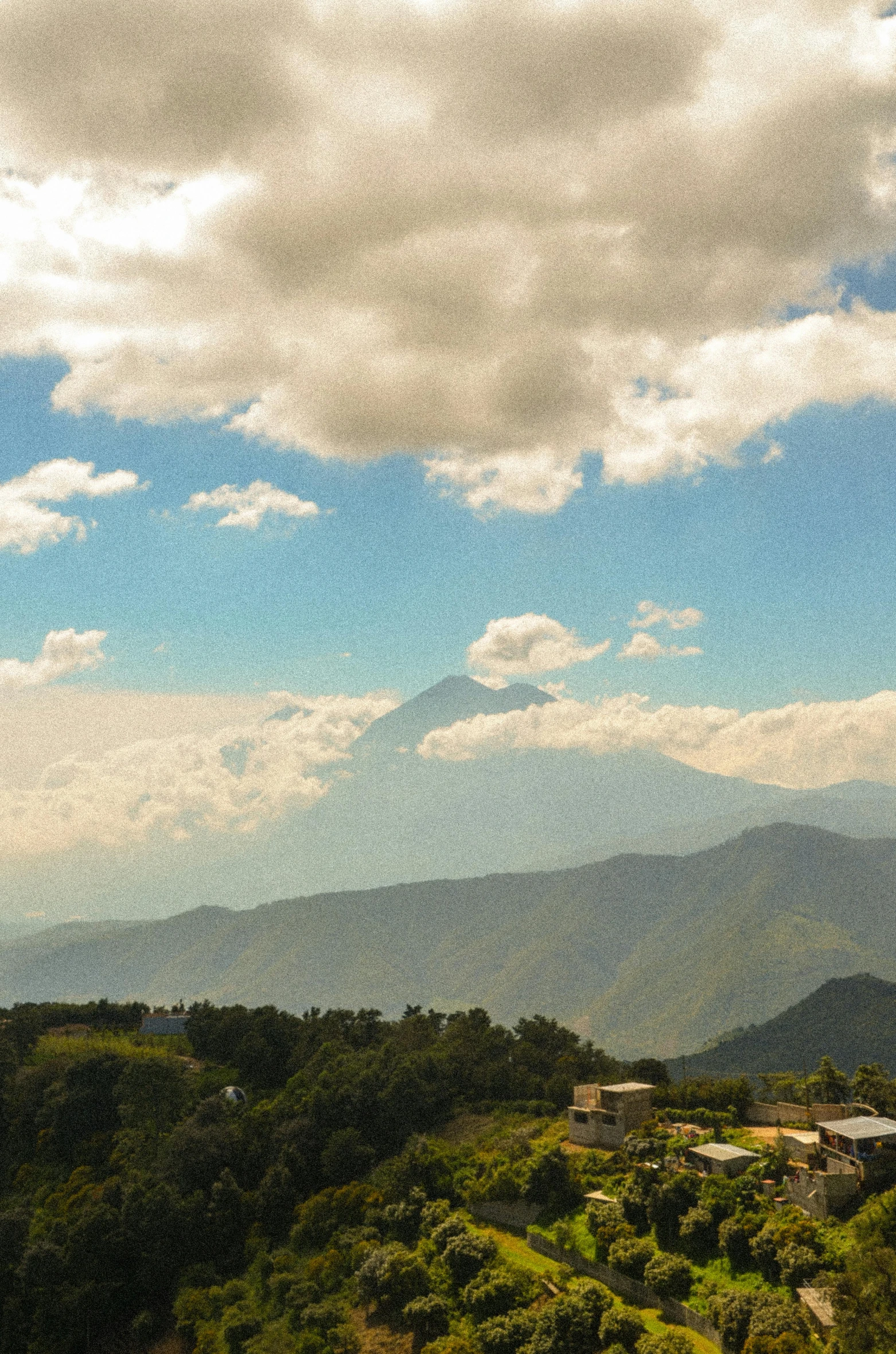 the sky is partly cloudy over a village on a mountain top