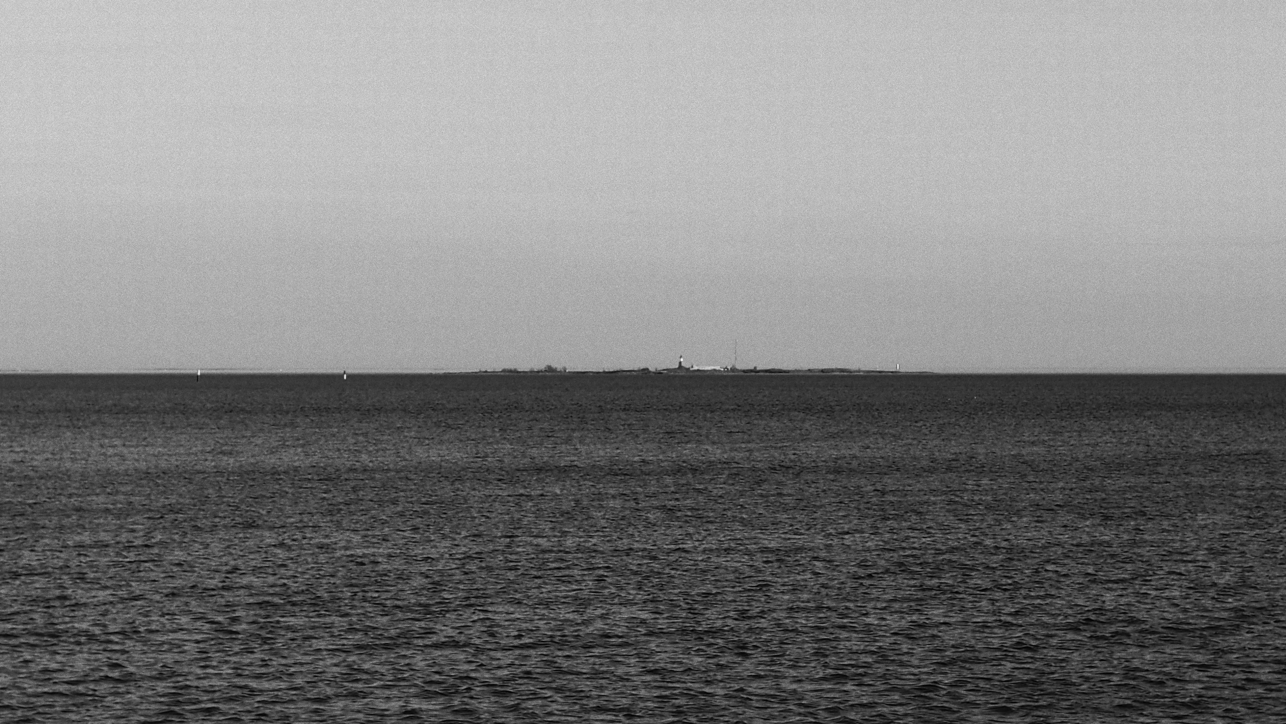 a black and white picture of an ocean with one sailboat