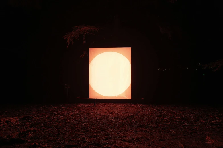 a lighted doorway in the middle of an open field at night