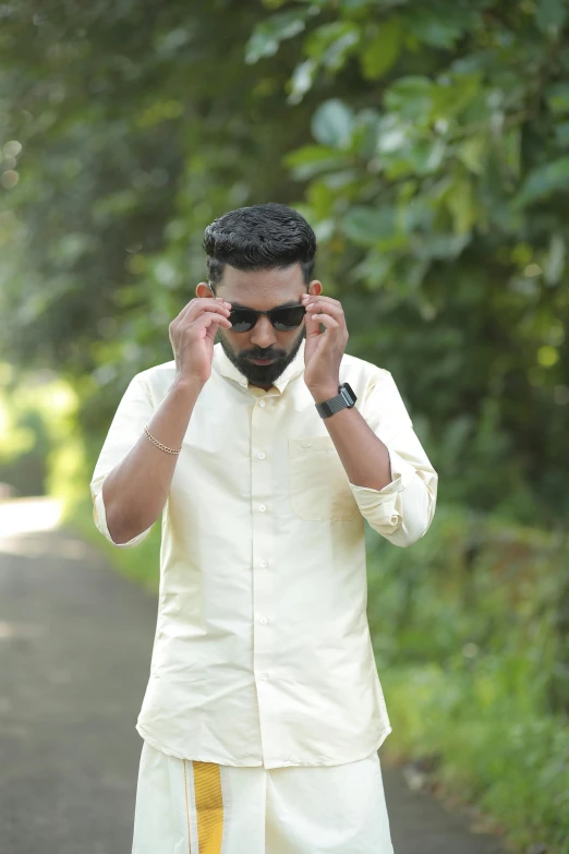 a man with sun glasses on standing in the middle of a road