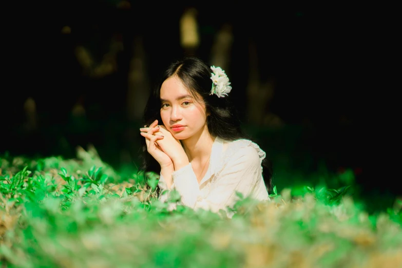 young lady in white with her hand to her face lying down