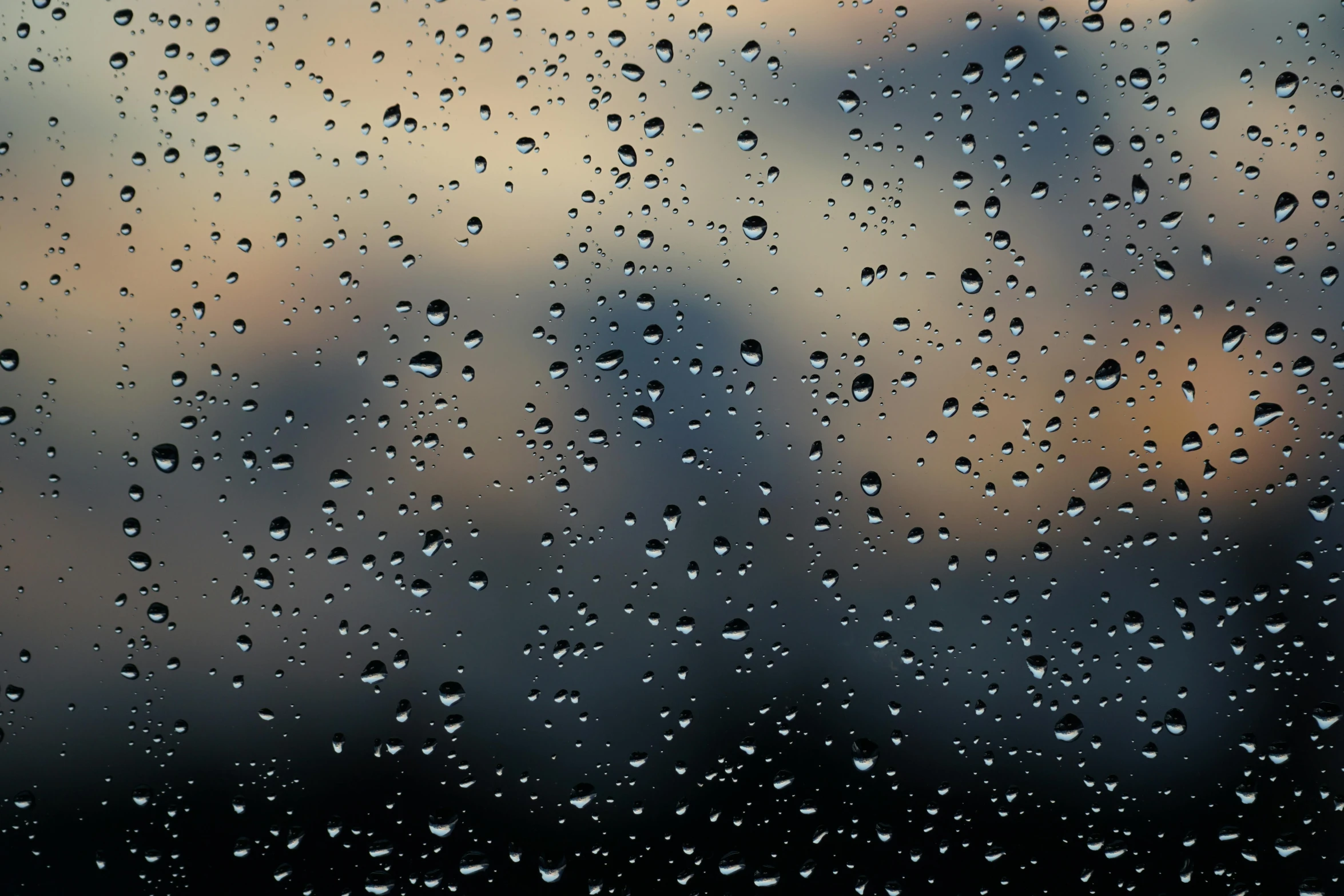 a rainy window with rain drops falling on it