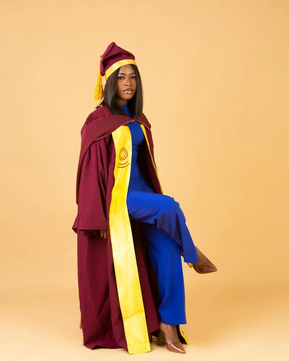 a female in a brown graduation gown and yellow hat