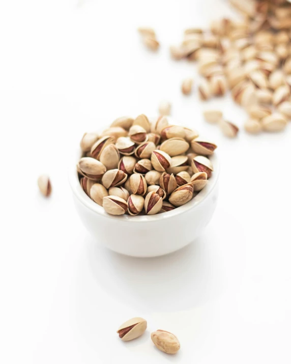 a white bowl filled with nuts next to two pile of nuts