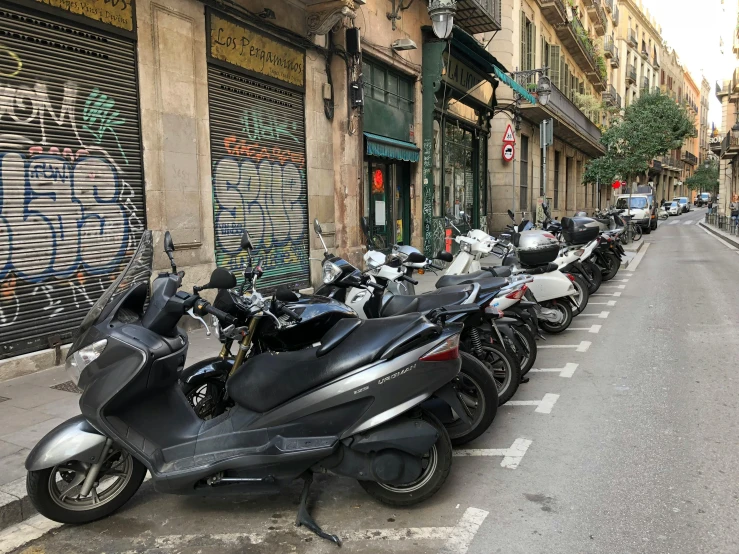 a row of motorcycles sit parked near a city street