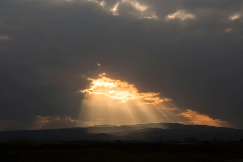 sun shining through some clouds with trees in front of it