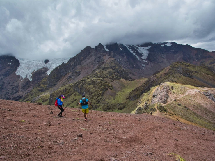 two hikers on a cloudy day descending a mountain trail