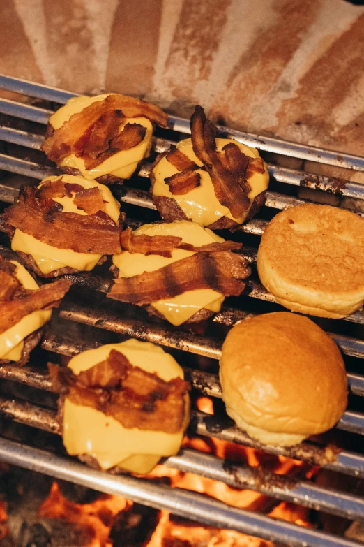 some hamburgers and buns sitting on a grill