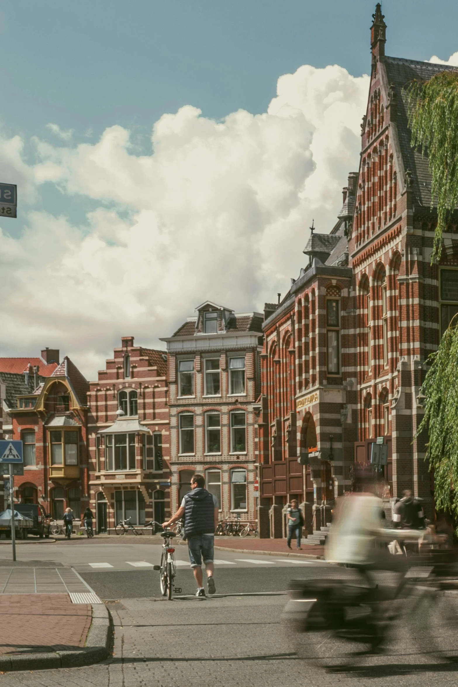 the bicycle rider rides past the old building in front of the motorcyclist