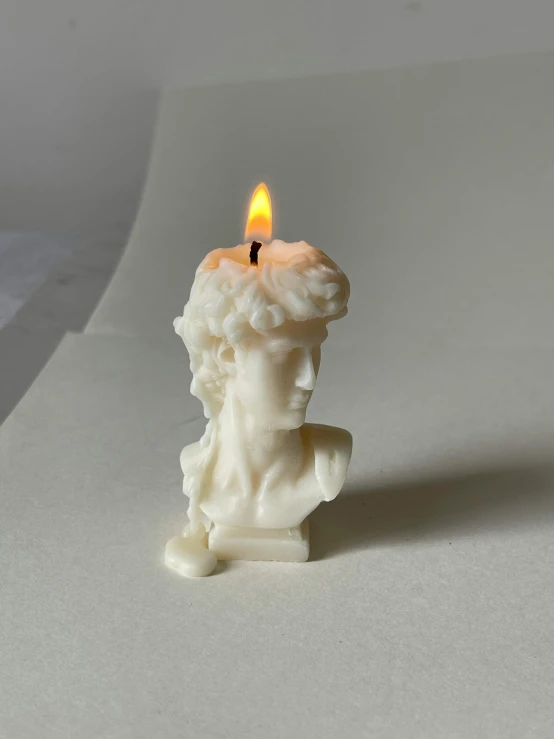 a white candle with a statue lit up