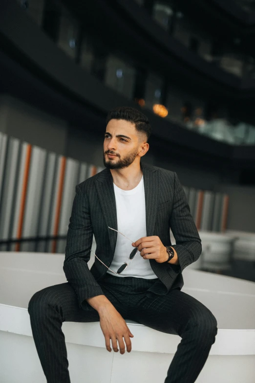 young man in black suit and white shirt is sitting