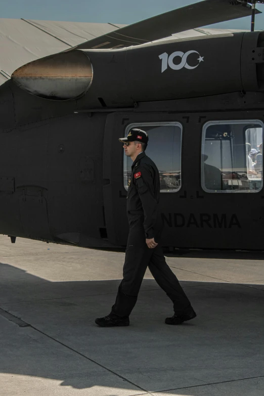 a man in uniform walking towards a black helicopter