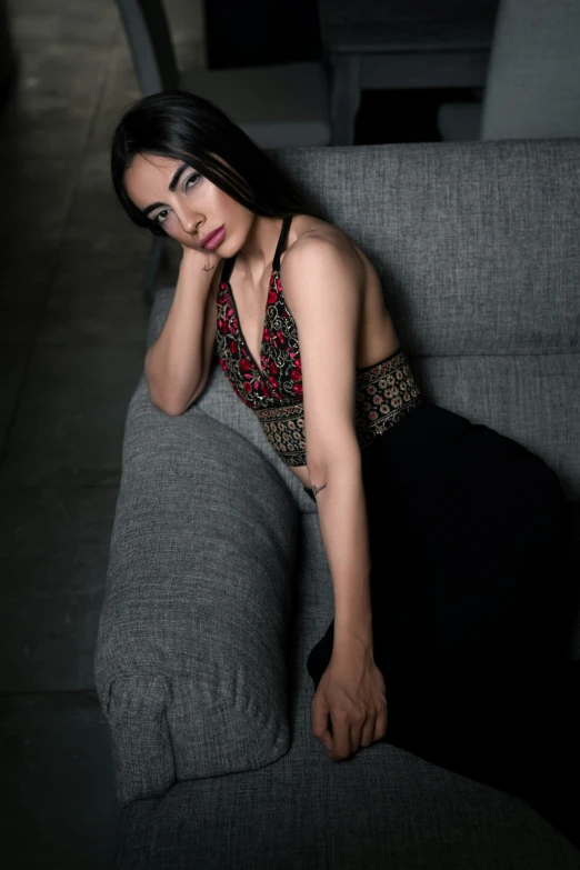 a woman in black dress sitting on a gray couch