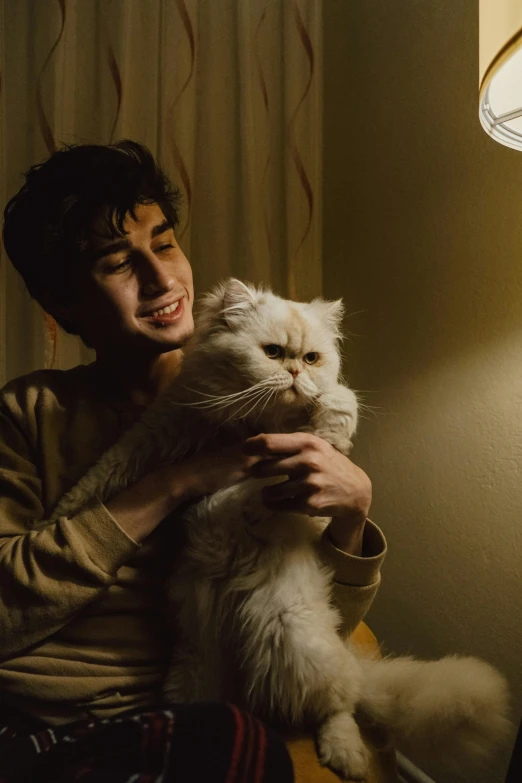 a man holding a white cat in his arms and smiling at the camera