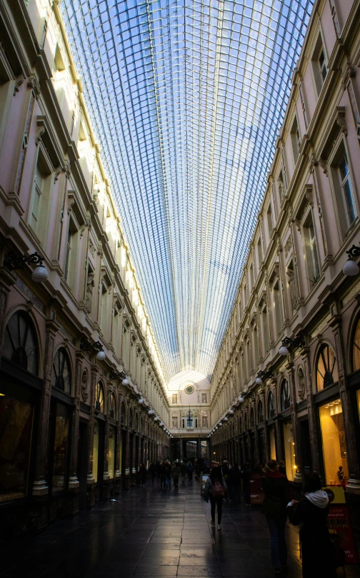 people are walking inside a large building with many ceiling lights