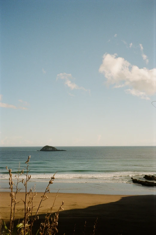 the beach has waves crashing in front of a small island