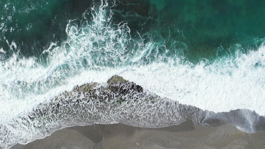aerial view of waves crashing onto an ocean beach