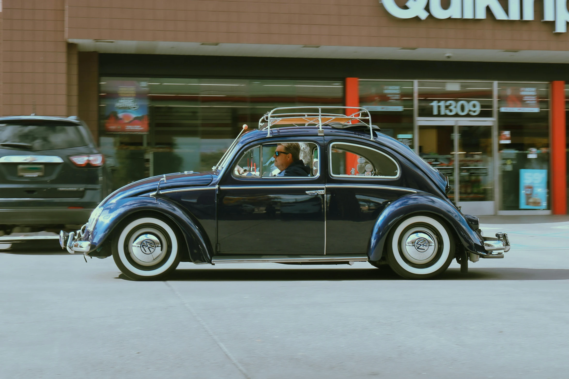 blue car in a parking lot with storefront in the background