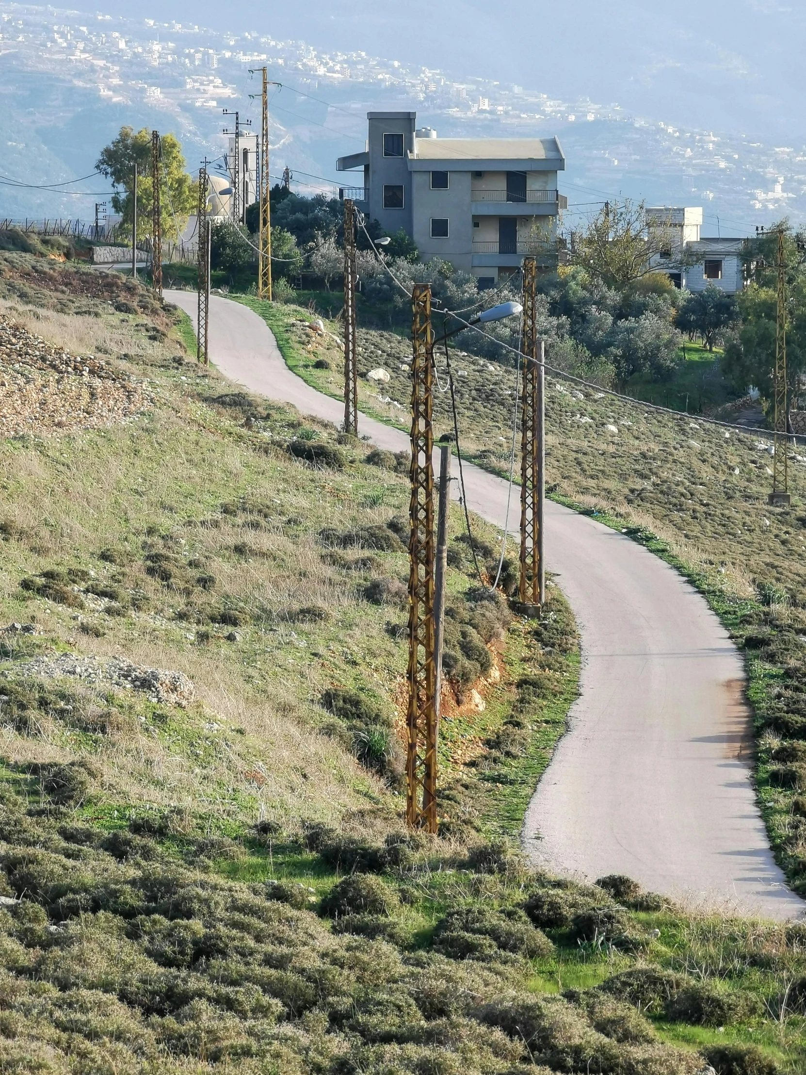 an winding road in a dry area with a hillside in the distance