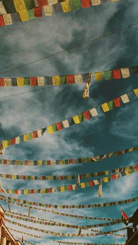 many colored flags in the air next to a clock tower